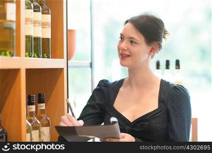 Shop assistant in wine shop doing stock taking