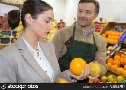 Shop assistant passing grapefruit to customer