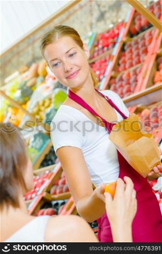 Shop assistant passing orange