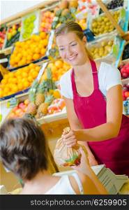 Shop assistant serving customer with fruit and veg