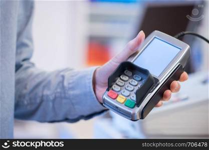 Shop owner is holding a payment terminal in his hand