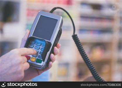 Shop owner is holding a payment terminal in his hand