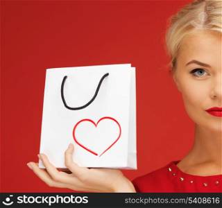 shopping and happiness concept - lovely woman in red dress with shopping bag and heart on it
