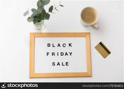 shopping and marketing concept - white magnetic board with black friday sale words, credit card and cup of coffee on table. board with black friday sale words and credit card