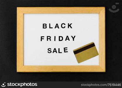 shopping and marketing concept - white magnetic board with black friday sale words and credit card. board with black friday sale words and credit card