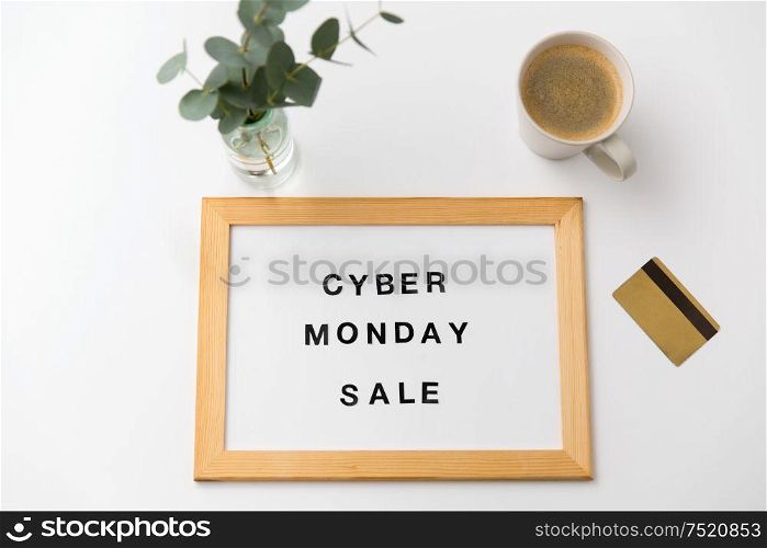 shopping and marketing concept - white magnetic board with cyber monday sale words, credit card and cup of coffee on table. board with cyber monday sale words and credit card