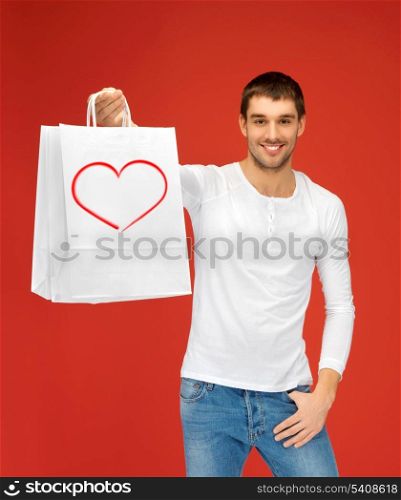 shopping and relationships concept - handsome man with shopping bags and heart on it