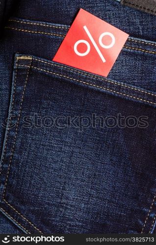 Shopping and sale concept. Closeup red label with percent sign on navy blue jeans pocket denim cotton material background
