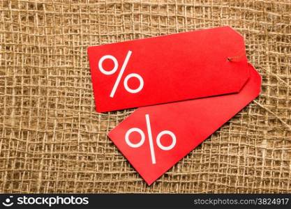 Shopping and sale concept. Two red price labels with percent sign on cloth burlap surface background. Copyspace