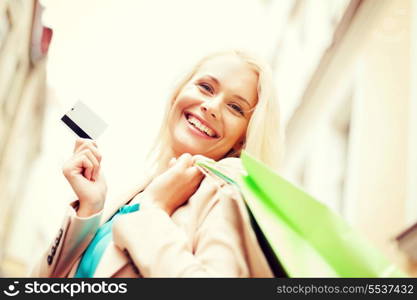 shopping and tourism - beautiful woman with shopping bags and plastic card in city