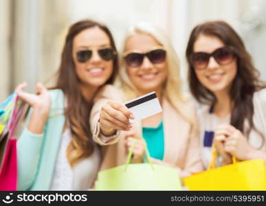 shopping and tourism concept - beautiful girls with shopping bags and credit card in ctiy