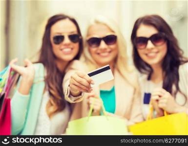 shopping and tourism concept - beautiful girls with shopping bags and credit card in ctiy