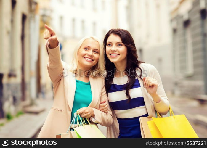 shopping and tourism concept - beautiful girls with shopping bags in city