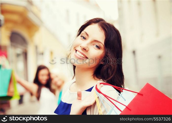 shopping and tourism concept - beautiful girls with shopping bags in city