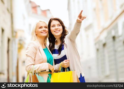 shopping and tourism concept - beautiful girls with shopping bags in ctiy