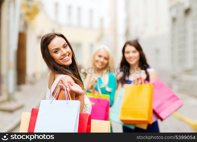 shopping and tourism concept - beautiful girls with shopping bags in ctiy