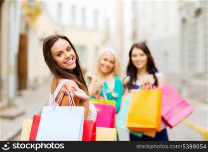 shopping and tourism concept - beautiful girls with shopping bags in ctiy