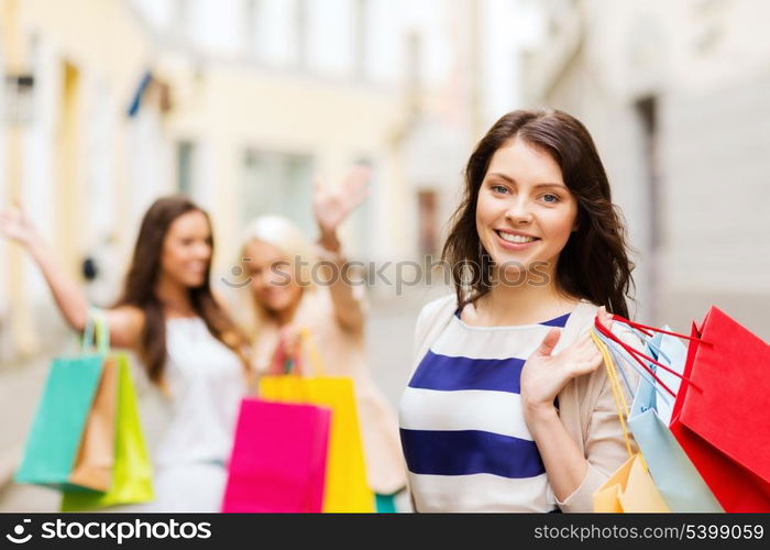 shopping and tourism concept - beautiful girls with shopping bags in ctiy