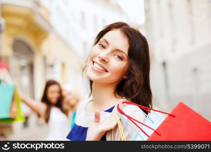 shopping and tourism concept - beautiful girls with shopping bags in ctiy