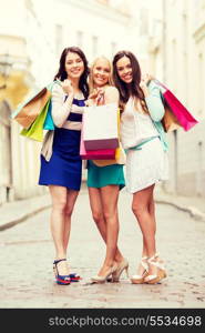 shopping and tourism concept - beautiful girls with shopping bags in ctiy