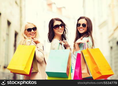 shopping and tourism concept - beautiful girls with shopping bags in ctiy