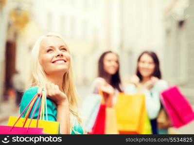 shopping and tourism concept - beautiful girls with shopping bags in ctiy