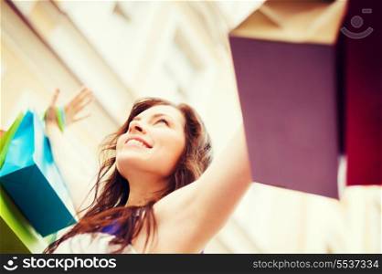 shopping and tourism concept - beautiful woman with shopping bags in city