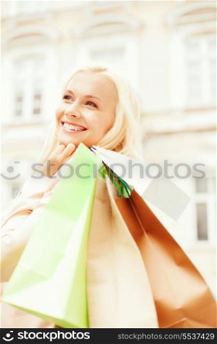 shopping and tourism concept - beautiful woman with shopping bags in city