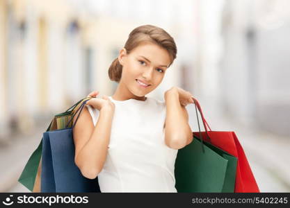 shopping and tourism concept - beautiful woman with shopping bags in ctiy