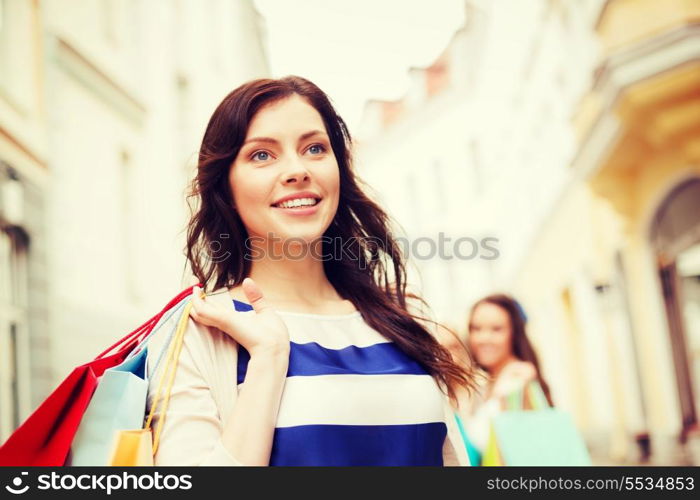 shopping and tourism concept - beautiful woman with shopping bags in ctiy