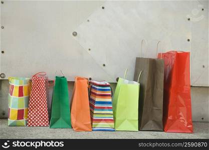 Shopping bags in front of a wall in a row
