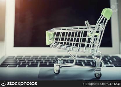 Shopping basket on top of laptop with free copy space. Online shopping and payment concept. E-commerce and global network business.