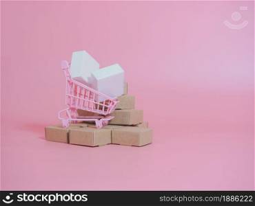 Shopping cart and boxes on pink background. Logistics and wholesale concept.