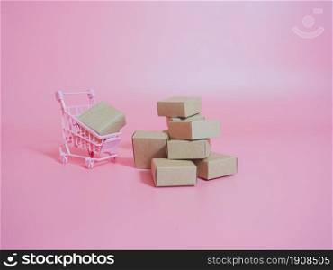 Shopping cart and boxes on pink background. Logistics and wholesale concept.