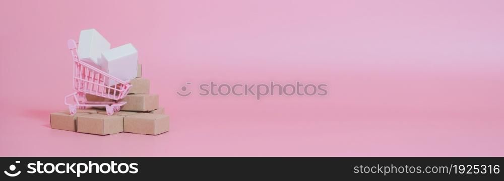 Shopping cart and boxes on pink background. Logistics and wholesale concept. web banner size.