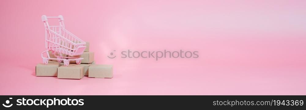 Shopping cart and boxes on pink background. Logistics and wholesale concept. web banner size.