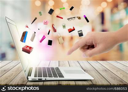 Shopping cart and laptop computer with products on wood bokeh background, shop online concept.