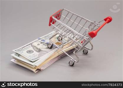 Shopping cart on money (dollar, euro) isolated on gray background