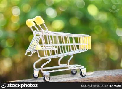 Shopping cart on nature green bokeh background / Online shopping Black Friday concept with yellow Shopping cart on wooden - Shopping vacation