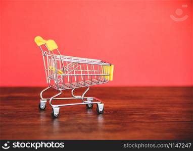 Shopping cart on wooden / Online shopping Black Friday concept with yellow Shopping cart on red background - Shopping vacation