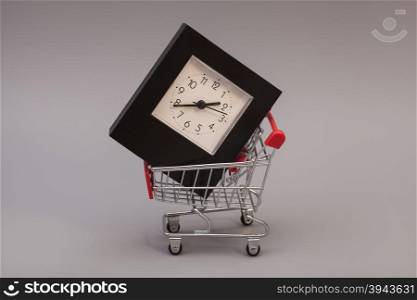 Shopping Cart with Alarm Clock on gray background