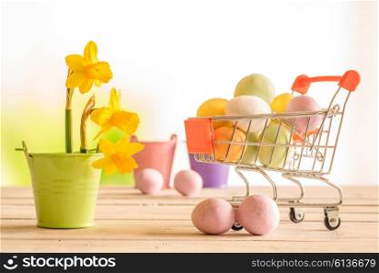 Shopping cart with colorful easter eggs and daffodils in a flowerpot