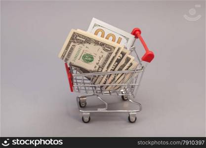 Shopping Cart with dollars isolated on gray