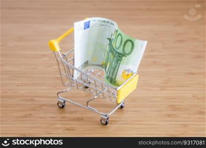 Shopping cart with eur banknote on wooden table