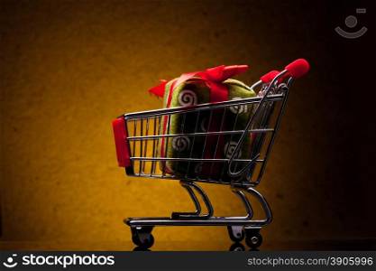 shopping cart with gift on yellow background