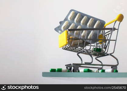 Shopping cart with medical pills on white mirror background. Shopping cart with medical pills on a white mirror background