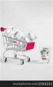 shopping cart with pill blister medicines glass white background