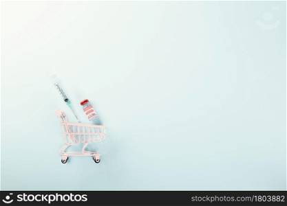 Shopping cart with vaccine vials bottles for vaccination, vaccine reservation concept, buy vaccine, vaccine requirements studio shot isolated blue background with copy space for text