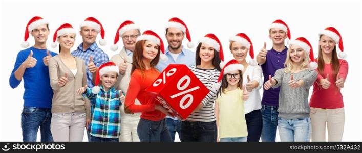 shopping, christmas sale and holidays concept - group of people in santa hats with percentage sign showing thumbs up. people with shopping bags at christmas sale