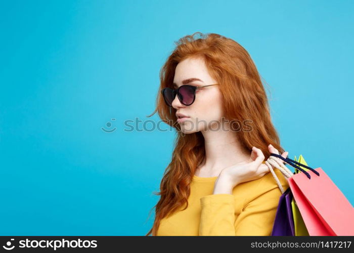 Shopping Concept - Close up Portrait young beautiful attractive redhair girl smiling looking at camera with shopping bag. Blue Pastel Background. Copy space.